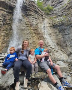 Family posing in front of a waterfall in Provo Canyon Utah.